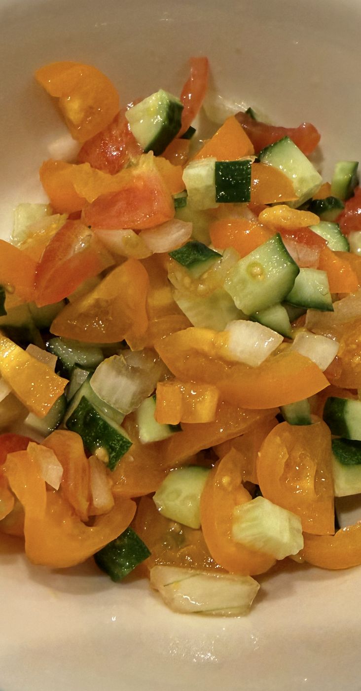Diced cucumber and orange pepper salad in a white bowl